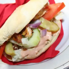 Pyszny kebab z kurczakiem, warzywami i kremowym sosem mieszanym do kebaba, zawinięty w czerwoną serwetkę.