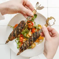 Dwie porcje soczystego mięsa wołowego kebab na patyczkach, podane z sałatką z pomidorków i papryczki chili.