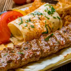 Soczysty kebab na talerzu z ryżem, warzywami i plackiem. Zastanawiasz się, ile kalorii ma kebab?