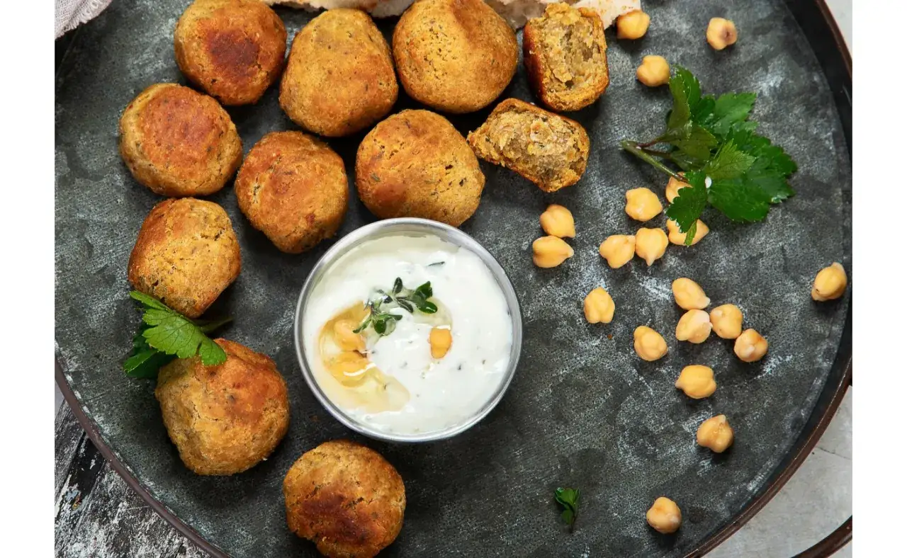 Co to jest falafel? Złociste kulki z ciecierzycy, podane z kremowym sosem jogurtowym i świeżą natką pietruszki.