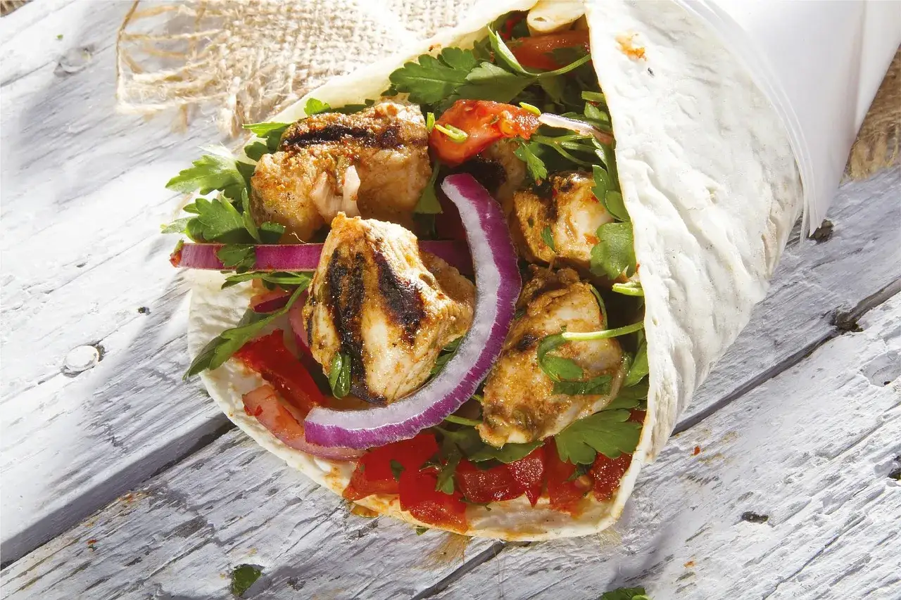 Pyszny kebab z grillowanym kurczakiem, świeżymi warzywami i ziołami, zawinięty w tortillę. Idealny sposób, jak zawijać kebaba w tortilli.