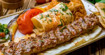Soczysty kebab na talerzu z ryżem, warzywami i plackiem. Zastanawiasz się, ile kalorii ma kebab?