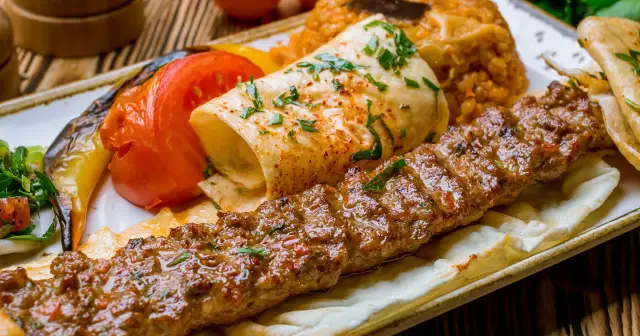 Soczysty kebab na talerzu z ryżem, warzywami i plackiem. Zastanawiasz się, ile kalorii ma kebab?